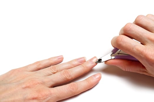 Woman's hand removing nail cuticle on light white table. Care about dry, overgrown cuticle. Closeup