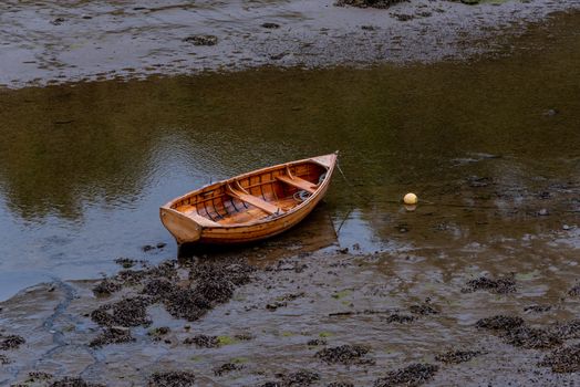 Rowboat is anchored in muddy water.