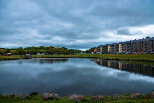 Westport, Ireland -- July 14, 2018. Shops and hotels from the resort area of Westport are reflected in a pond.