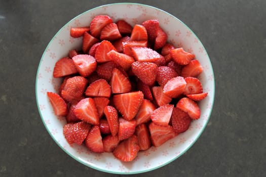 Sliced fresh red strawberries in a porcelain bowl
