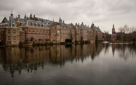 Dutch parliament on overcast day reflected in water on nearby lake