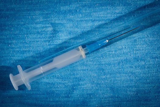 Disposable medical syringe on a blue background
