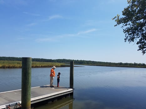 father and son on dock or pier with lake or river water