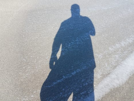 shadow of man or male on wet sand at beach with water