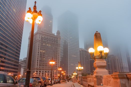 Chicago Illinois USA street as mist descends and lights come on Upper Wacker Drive with ornate lights tall buildings rising into fog