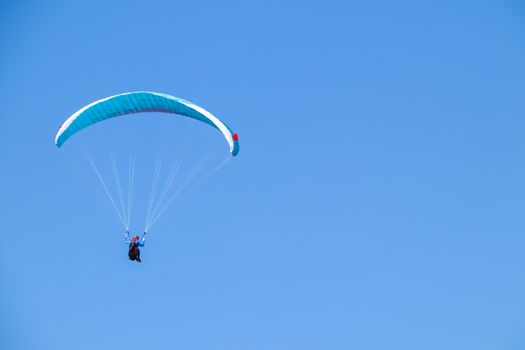 Paraglider soaring in the blue sky.