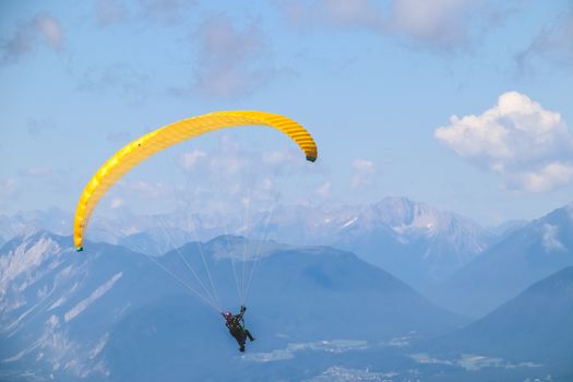 Paraglider soaring in the blue sky over the beautiful mountains.