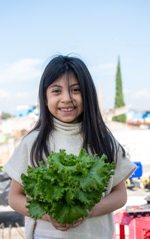 girl with lettuce on her hands in an urban garden