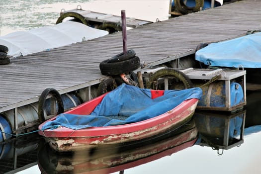 A red rowboot with blue tarpaulin on wooden jetty