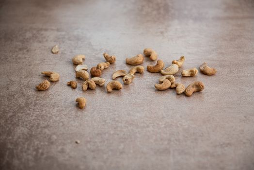 lots of cashews scattered on grey background with place for text