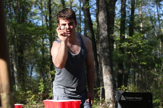 young man shoots for beer pong in a camping scene
