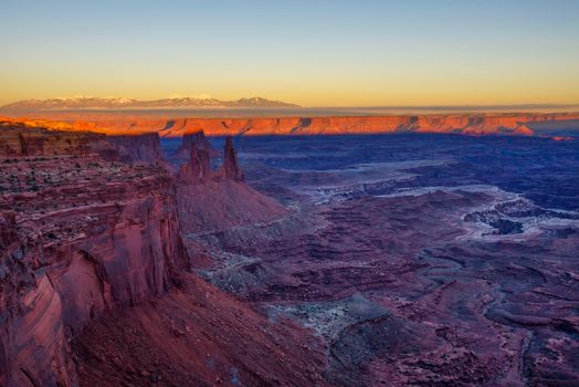Sunset above Canyonlands National Park near Moab, Utah with snow covered Rocky Mountains in the background.