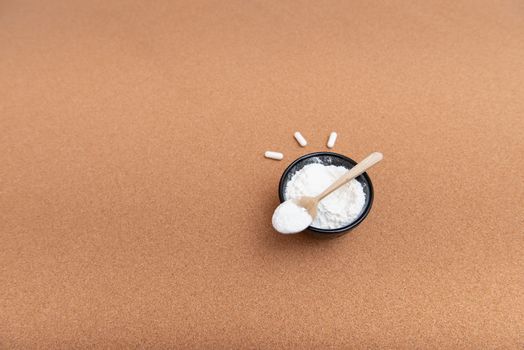 Collagen powder on a wooden spoon with empty place for text