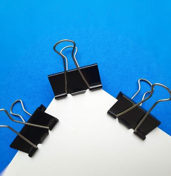 Three Black paper clips or chart clips arranged in white and blue background