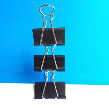 Three Black paper clips or chart clips arranged vertically in white and blue background