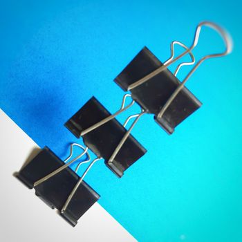 Three Black paper clips or chart clips arranged diagonally in white and blue background