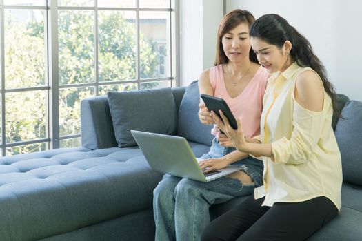 Two attractive Asian women are talking at home happily. Freelance women share casual wear, meetings, and computer technology together. learning use the internet  chatting with people on social media