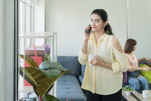 Portrait of an attractive, mature Asian woman talking on the phone and smiling happily at home on the fresh morning air and copy space.