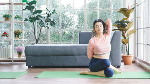 Attractive middle-aged women in Asia practice yoga, sit meditation For a balanced life at home. Sporty wears Sportswear to stretch the body with asana administration positions.