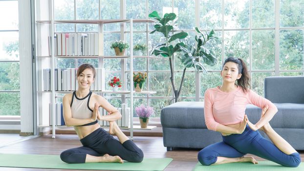 Attractive middle-aged women in Asia practice yoga, sit meditation For a balanced life at home. Sporty wears Sportswear to stretch the body with asana administration positions.