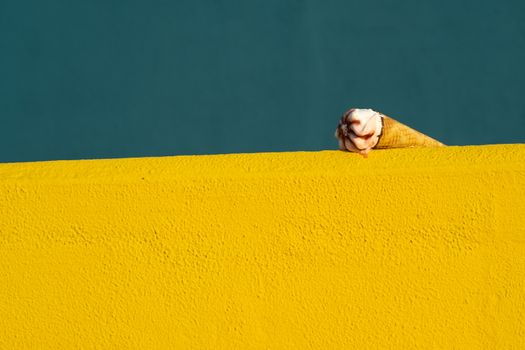 Ice cream with a cone melting in summer with the heat of the sun on a yellow and blue background. Vacation concept