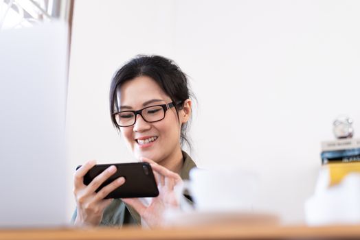 Modern young Asian woman playing a game instead of working from home with happy and fun.