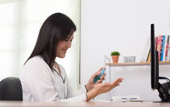 A beautiful Asian businesswoman cleaning hands by cleaner gel to protect COVID-19 before start working from home with safety and happiness.