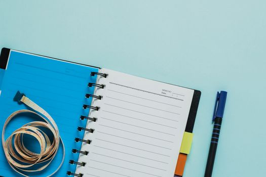 Notebooks with measure tape on blue background for healthy diet taking notes concept