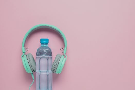 Fresh drinking water with headphones on pink background for healthcare and relaxation concept