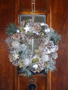 Christmas wreath hanging on a wooden door during the festive season celebrating the nativity of Jesus Christ stock photo                       