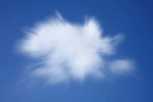 Background texture of a one single fluffy cumulus cloud in a blue clear sky with a zoom burst streak blur effect stock photo