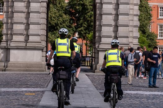 Dublin, Ireland --July 9, 2018. Guards from Trinity College enter a common area on bicycles.
