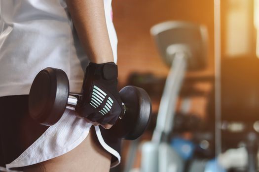 Close up woman are lifting dumbbells in the fitness room.