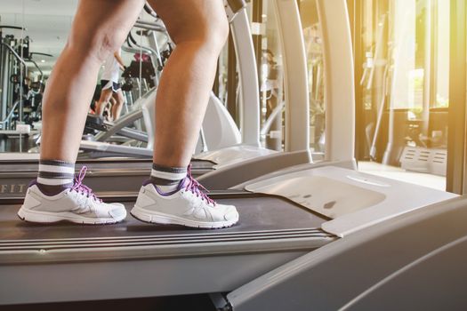 Close up shoes woman's running on treadmill. Woman with muscular legs in gym