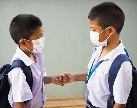 Students wearing masks to protect against viruses and  fist bumping. It's a new greeting during the COVID-19 virus outbreak. new normal concept. Corona virus.