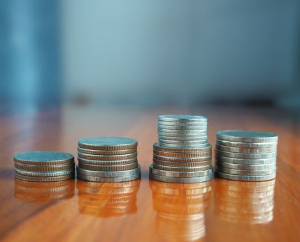 Silver coin arranged in a row laid on a brown wooden floor.
Financial, banking and business concepts.