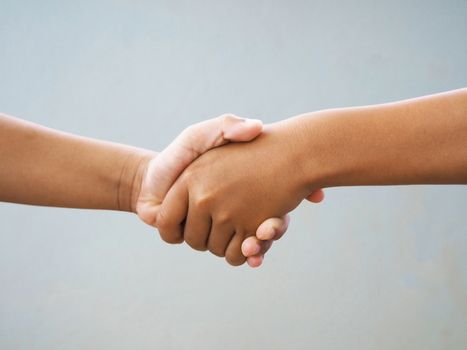 Two male hands shaking isolated on blue studio background. Social concepts.