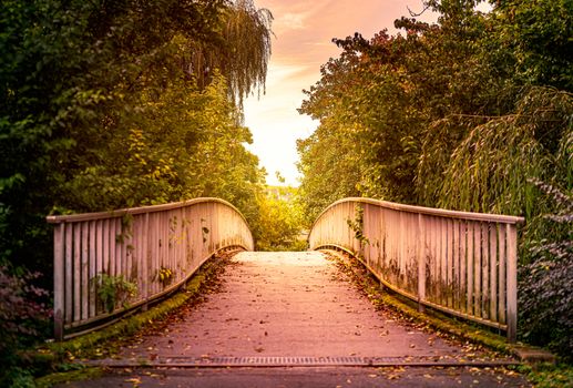 Old bridge in park of in town of Bad Mergentheim, Bavaria, Germany, Europe. Sunset cloudy sky in background