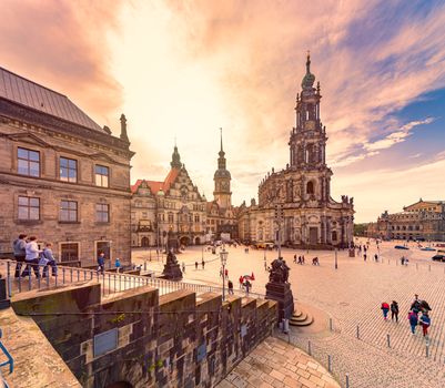 DRESDEN, GERMANY - SEPTEMBER 22, 2014: Katholische Hofkirche with Dresden Castle on the left and Semperoper on the right. People walking at cathedral square. Travel and architecture in Europe