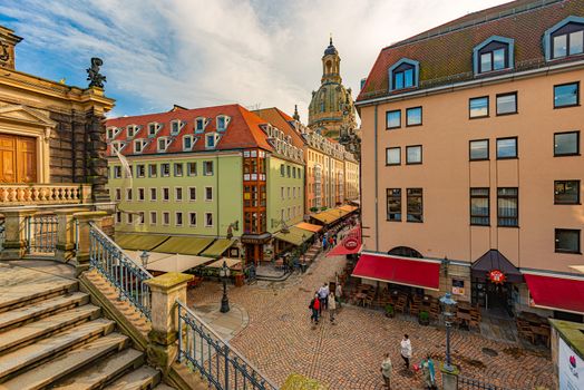 DRESDEN, GERMANY - SEPTEMBER 22, 2014: Old street with Frauenkirche cathedral in Dresden, Germany. Church of Our Lady is a Lutheran church in state of Saxony. View from square with people walking around