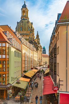 DRESDEN, GERMANY - SEPTEMBER 22, 2014: Old street with Frauenkirche cathedral in Dresden, Germany. Church of Our Lady is a Lutheran church in state of Saxony. View from square with people walking around