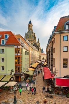 DRESDEN, GERMANY - SEPTEMBER 22, 2014: Old street with Frauenkirche cathedral in Dresden, Germany. Church of Our Lady is a Lutheran church in state of Saxony. View from square with people walking around