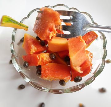 Orange color fresh papaya kept in white background with cut pieces in bowl with spoon and rich in fibre Vitamin C and antioxidants Boosts your immunity Good for diabetics and eyes