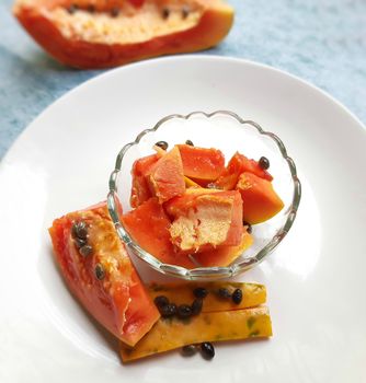 Orange color fresh papaya kept in white background with cut pieces in bowl and rich in fibre Vitamin C and antioxidants Boosts your immunity Good for diabetics and eyes