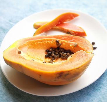 Orange color fresh papaya cut into half and cur pieces kept in white background and rich in fibre Vitamin C and antioxidants Boosts your immunity Good for diabetics and eyes