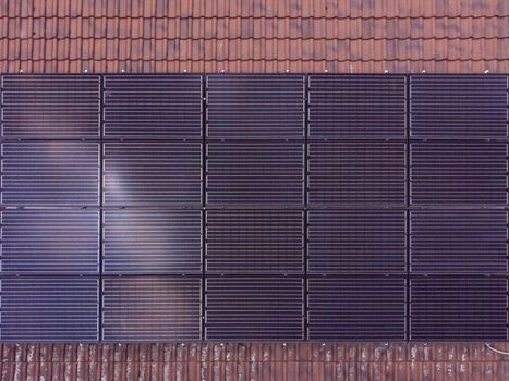 Black solar panels in rectangular shape installed on a tiled roof. Clean energy.