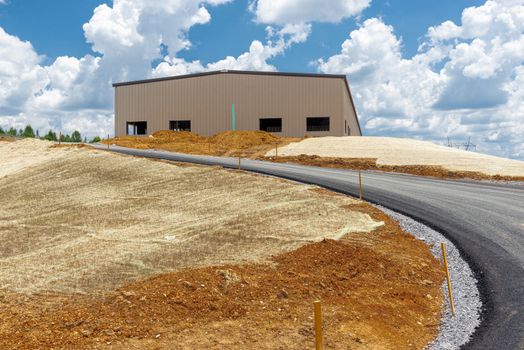 Horizontal shot of fresh blacktop leading to a newly constructed commercial structure.