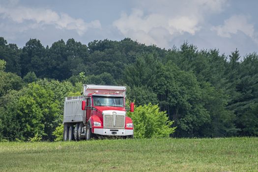 Red dump-truck on a hot summer day. Heat rising from highway surface creates an interesting wavy shimmering pattern on the truck and background.