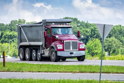 Horizontal shot of a large dump truck delivering gravel to a commercial construction site.