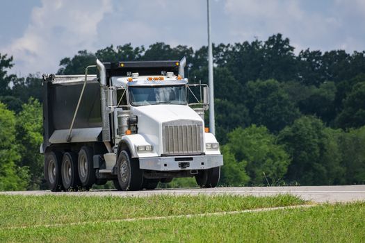 Horizontal shot of a loaded dump truck carrying gravel to a construction site.